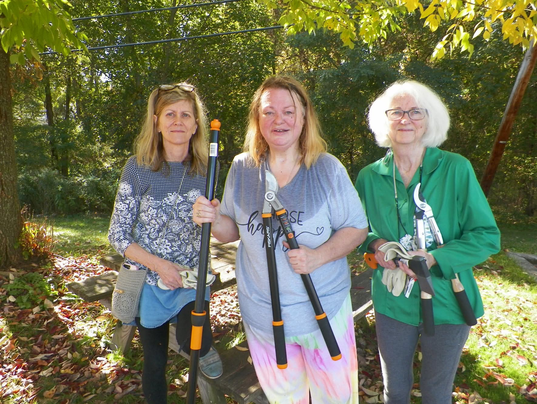 Photo of Jen Ward with Druid Brigade participants holding gardening tools