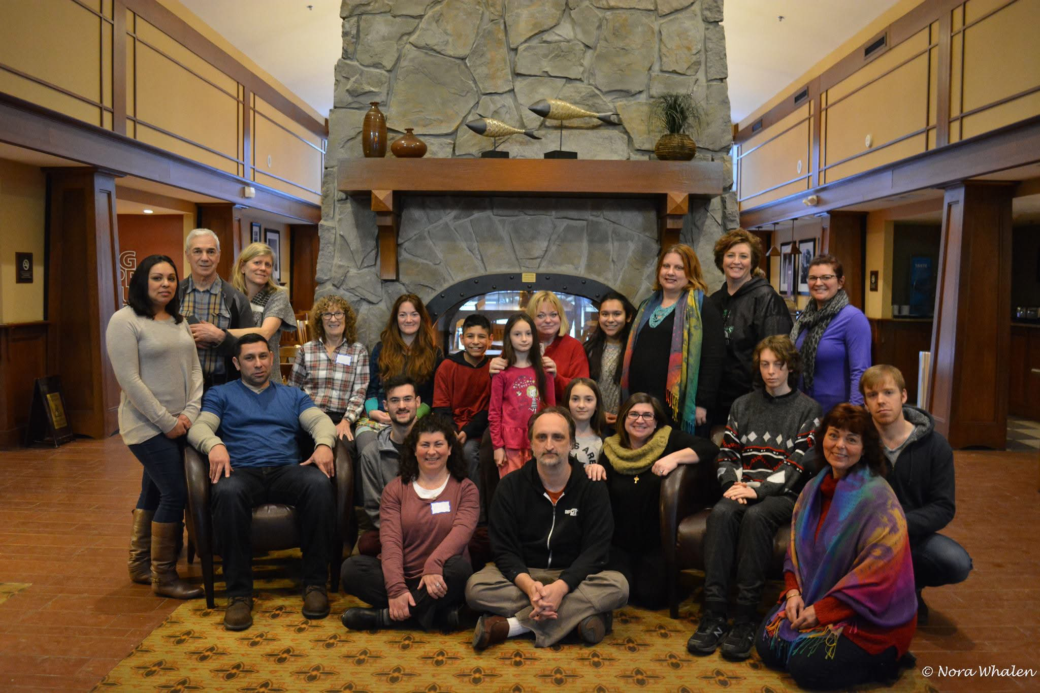 Group photo of Jen Ward and healing retreat participants in front of conference center fireplace