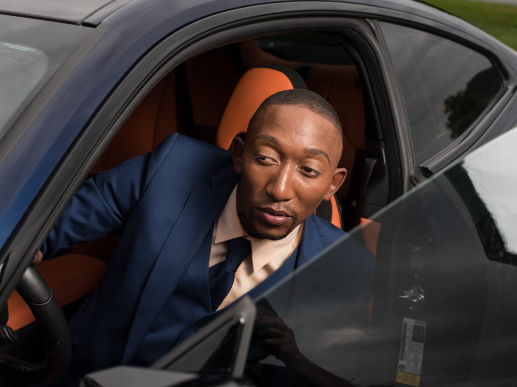 Photo of a man in a suit looking out from his car